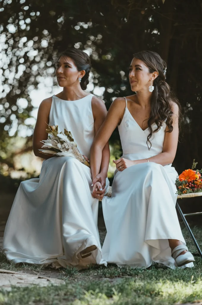 Deux mariées en robe blanche assises côte à côte pendant une cérémonie en extérieur