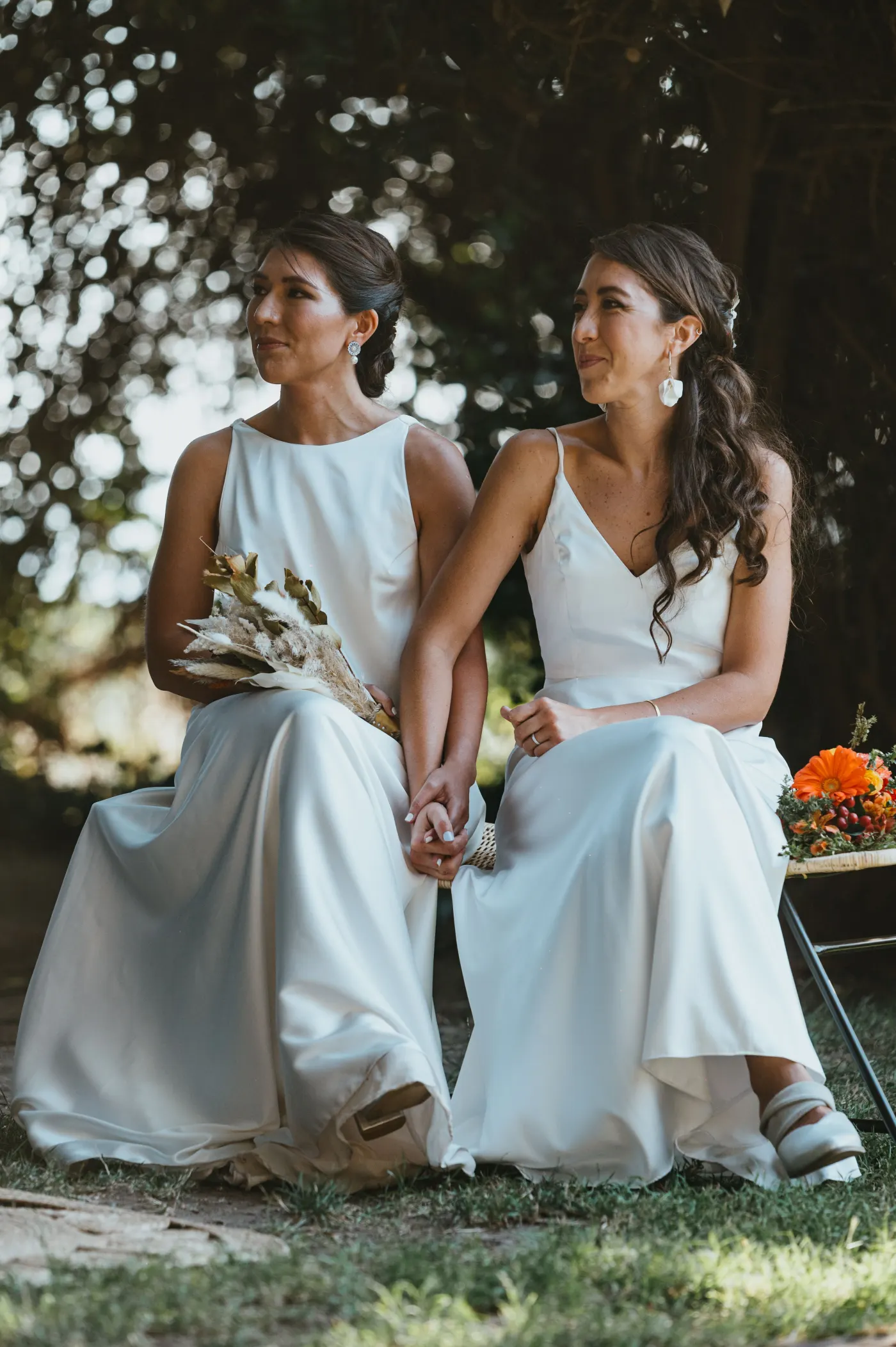 Deux mariées en robe blanche assises côte à côte pendant une cérémonie en extérieur